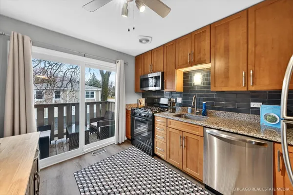 a kitchen with stainless steel appliances granite countertop a stove top oven a sink dishwasher a dining table and chairs with wooden floor