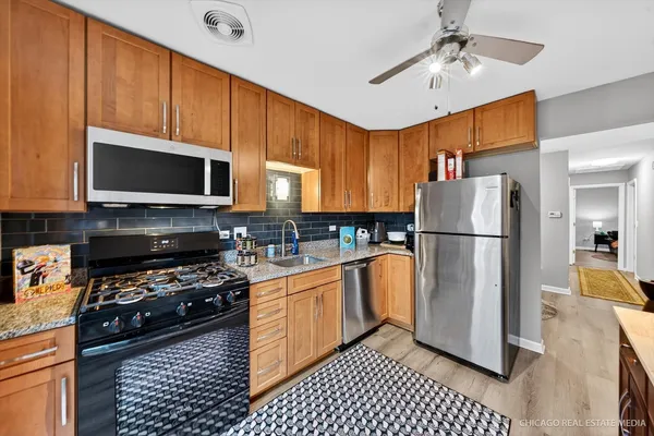 a kitchen with stainless steel appliances granite countertop a refrigerator a stove top oven a sink and cabinets