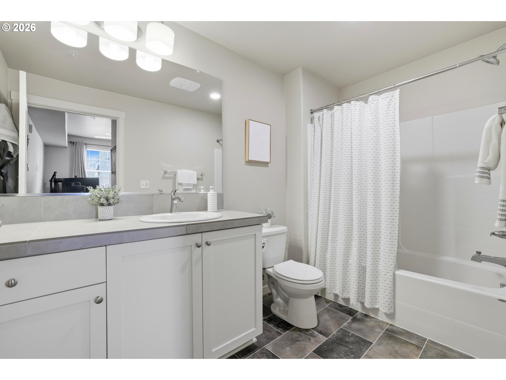 17149 Southwest Snowdale Street, Unit 103 Beaverton, OR 97007 - Photo 29 of 48 a bathroom with a sink a toilet a mirror a vanity and bathtub