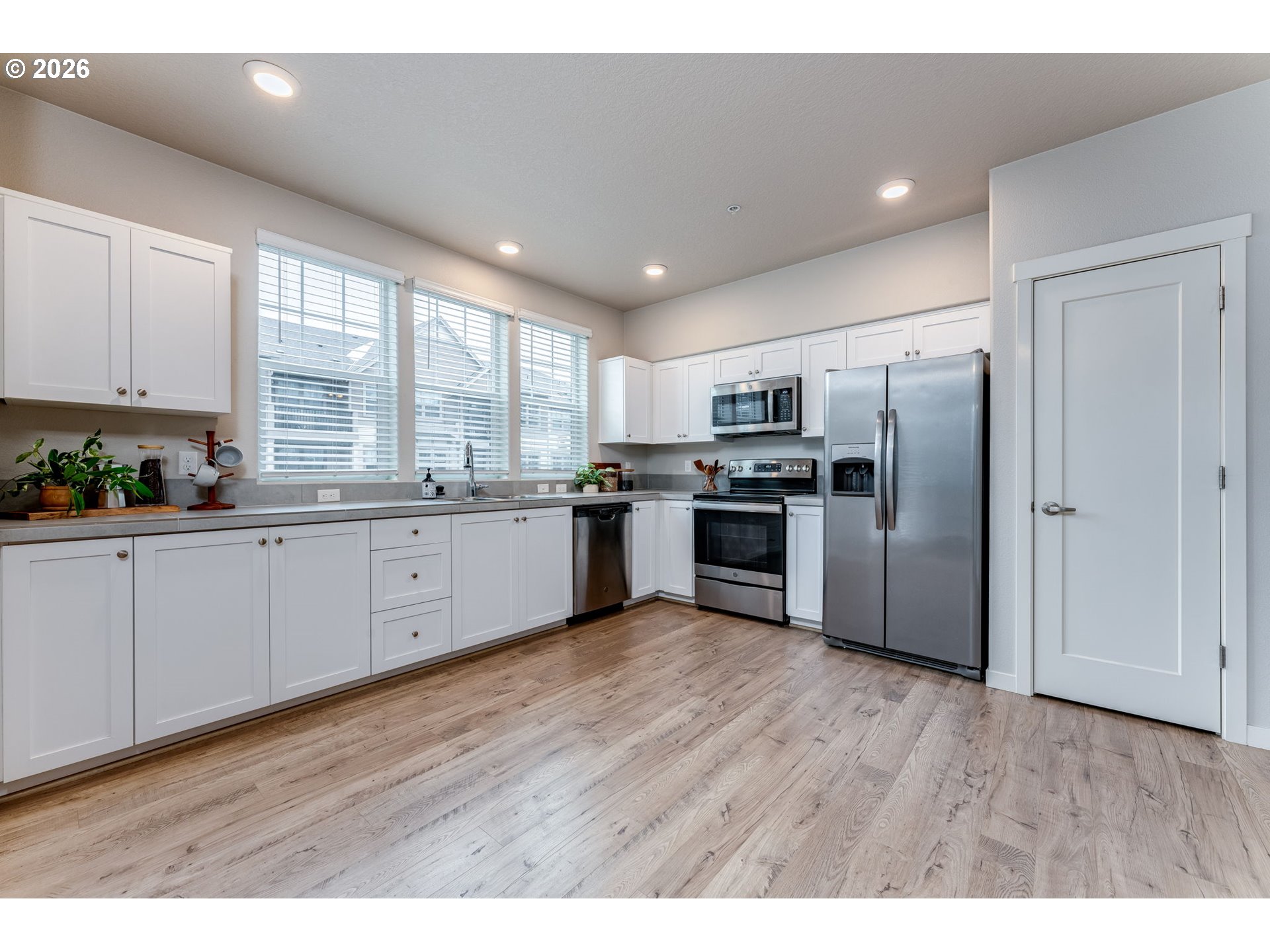 17149 Southwest Snowdale Street, Unit 103 Beaverton, OR 97007 - Photo 10 of 48 a kitchen with stainless steel appliances granite countertop a refrigerator a sink dishwasher a stove with cabinets next to a window