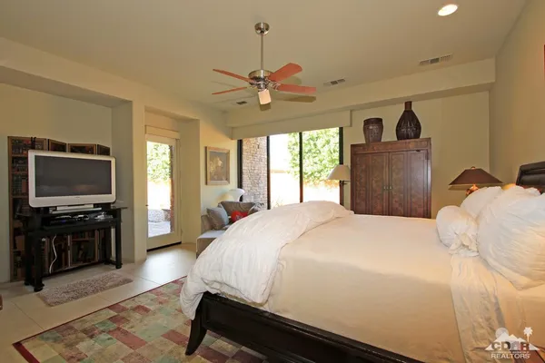 a bedroom with a bed a dresser and a chandelier