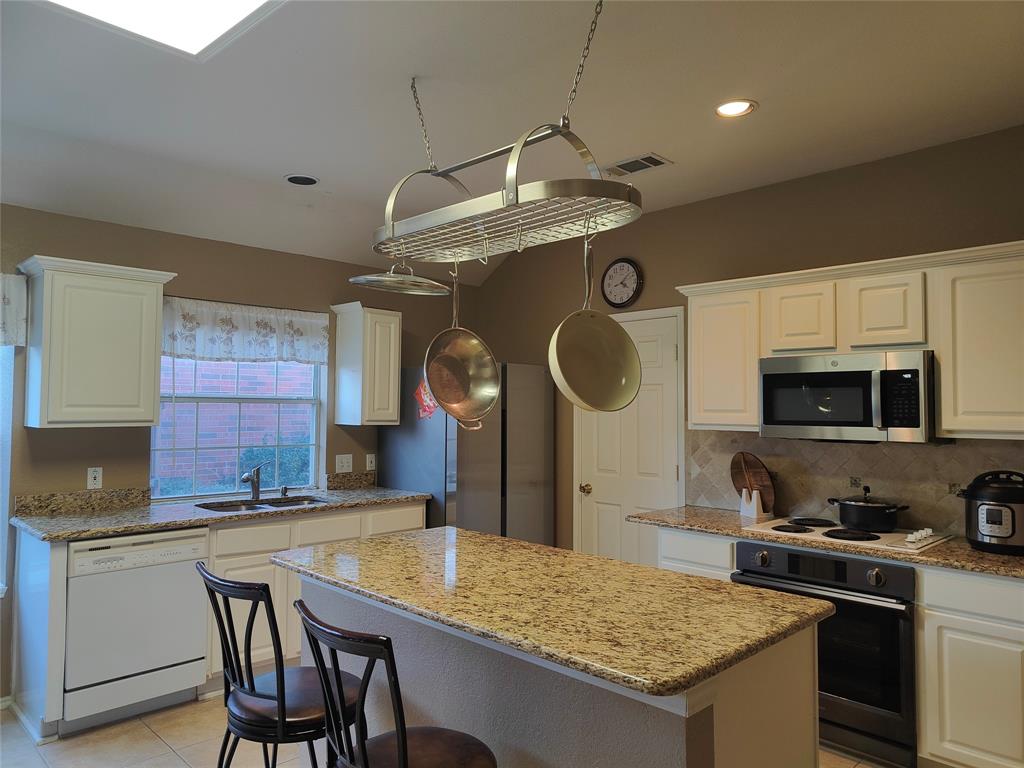 7900 Roaring Ridge Drive Plano, TX 75025 - Photo 7 of 34 a kitchen with stainless steel appliances granite countertop a stove a sink and a microwave