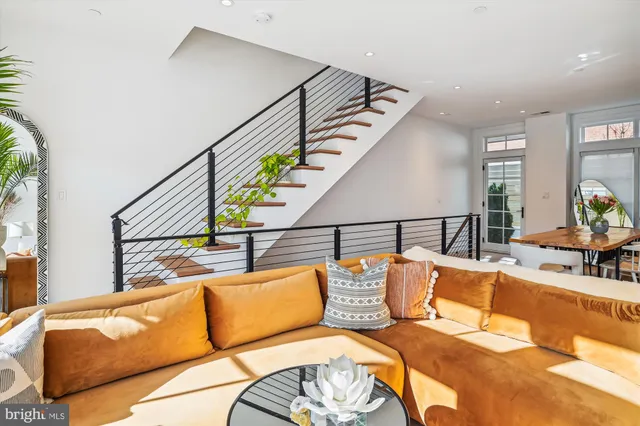 a living room with furniture large windows and kitchen view