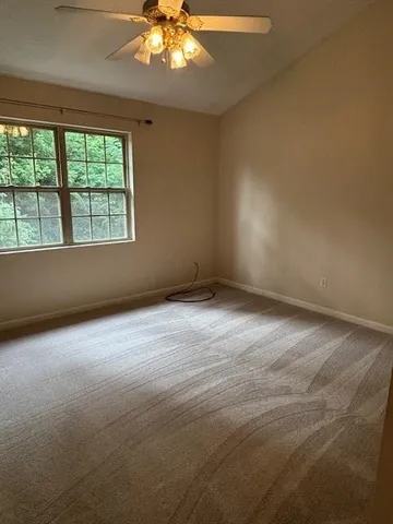 an empty room with a chandelier fan and windows