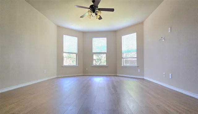 a view of an empty room with wooden floor and a window