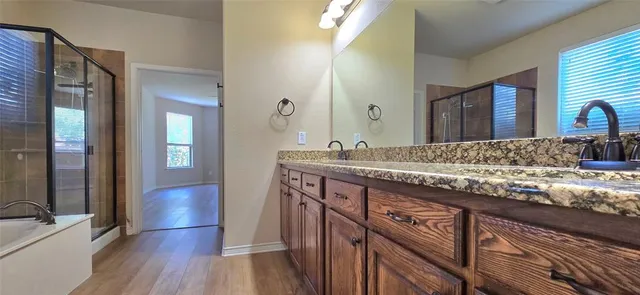a bathroom with sinks granite countertop wooden floor and a sink