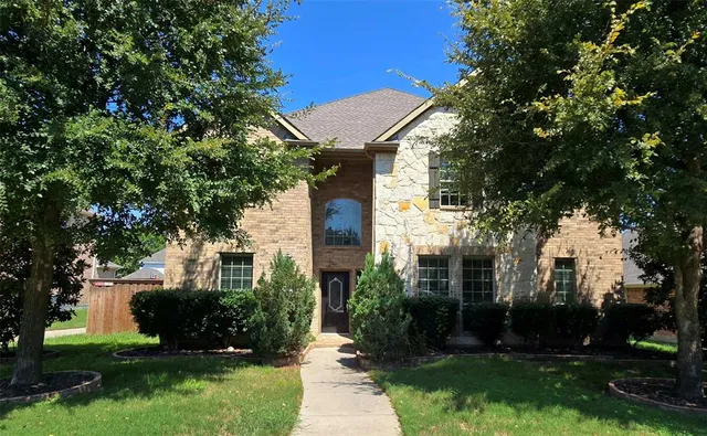 a view of a white house next to a yard with big trees