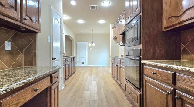 a kitchen with stainless steel appliances granite countertop a lot of counter space and wooden floors