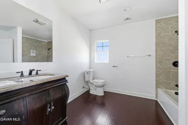 a bathroom with a granite countertop sink a toilet a shower and a mirror