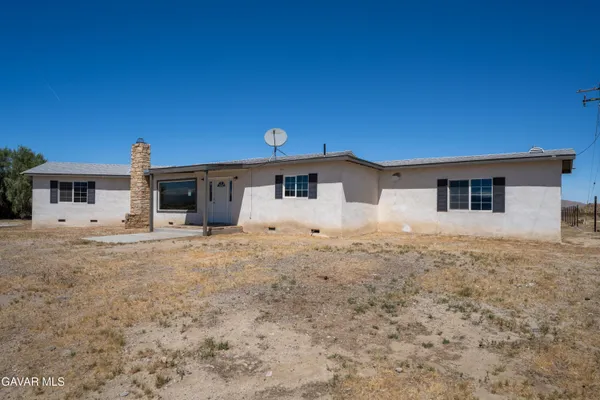 a front view of a house with a dirt road and a yard