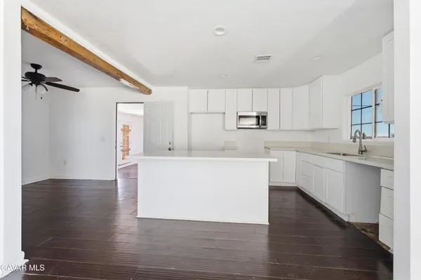 a large kitchen with a refrigerator a sink dishwasher a stove and white cabinets with wooden floor