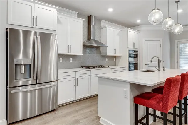 a kitchen with stainless steel appliances granite countertop a refrigerator a sink dishwasher a stove and white countertops with wooden floor