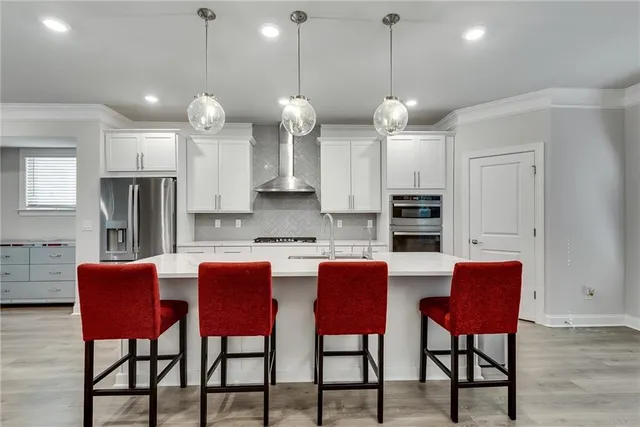 a kitchen with stainless steel appliances granite countertop a dining table chairs and white cabinets