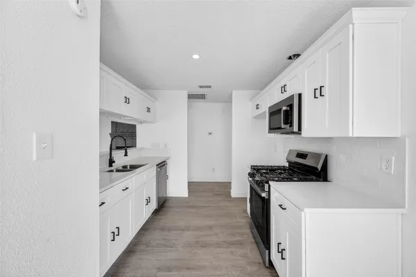 a kitchen with stainless steel appliances a sink stove and microwave