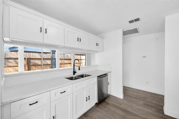 a kitchen with stainless steel appliances granite countertop white cabinets and window
