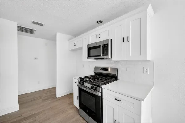 a kitchen with stainless steel appliances a white cabinet and a stove top oven