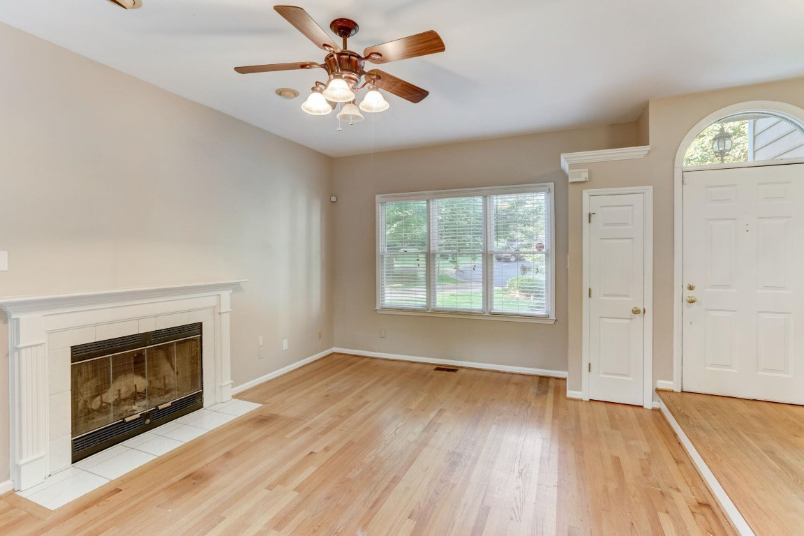 1601 Lethbridge Court Raleigh, NC 27606 - Photo 4 of 17 an empty room with wooden floor a fireplace and windows
