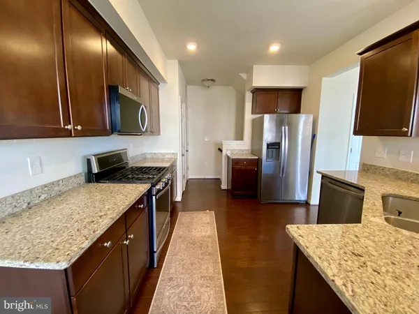 a kitchen with stainless steel appliances granite countertop sink stove refrigerator and cabinets