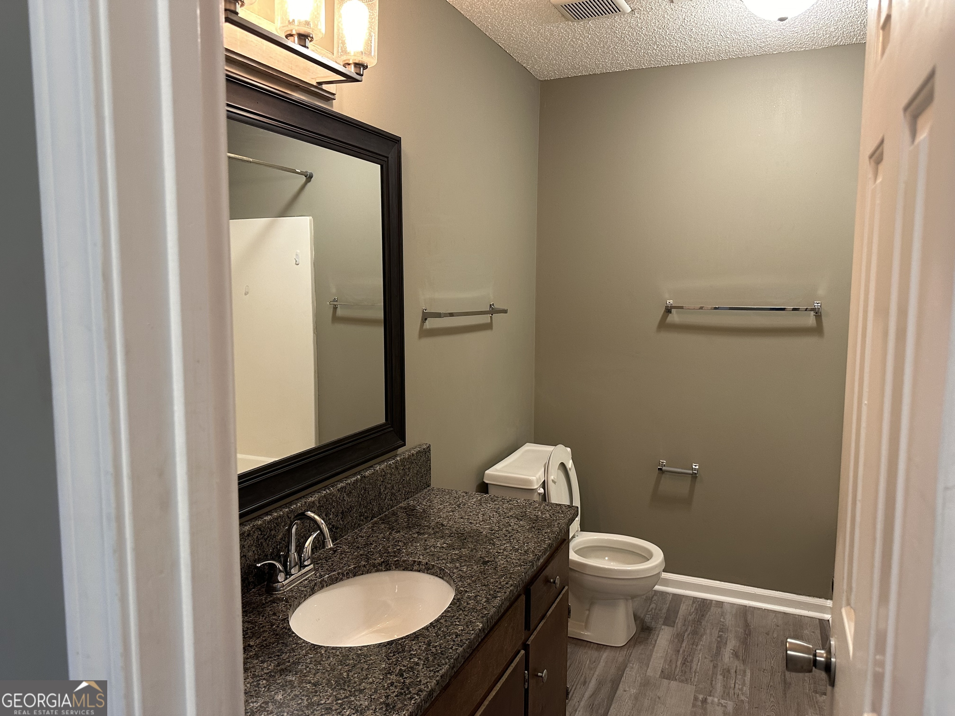 205 Maret Street Hartwell, GA 30643 - Photo 10 of 38 a bathroom with a granite countertop toilet a sink and mirror