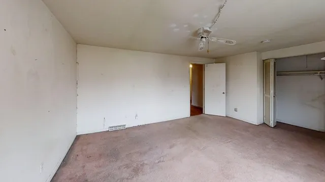 an empty room with a ceiling fan and window