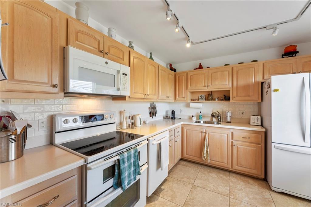 a kitchen with stainless steel appliances granite countertop white cabinets a sink a stove a refrigerator and cabinets