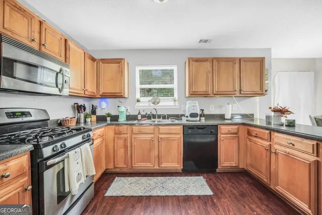 a kitchen with stainless steel appliances granite countertop a stove a sink dishwasher and a refrigerator