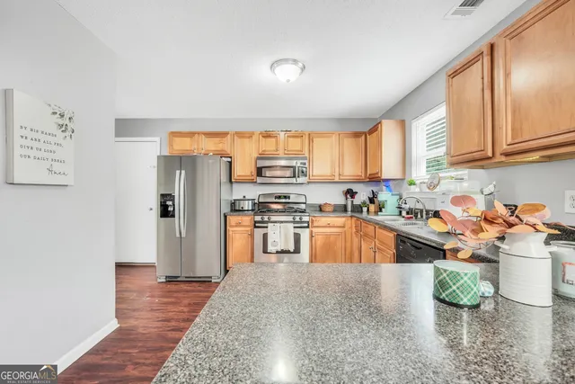 a kitchen with stainless steel appliances granite countertop a refrigerator sink and stove