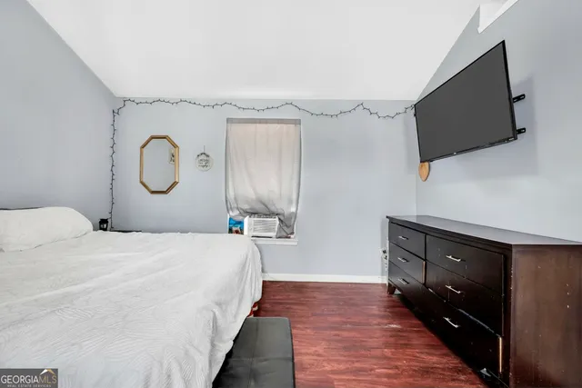 a bedroom with a bed and a flat tv screen on dresser