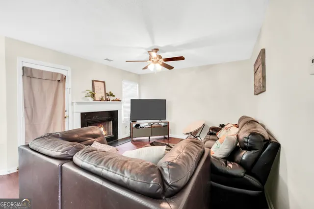 a living room with furniture a fireplace and a ceiling fan