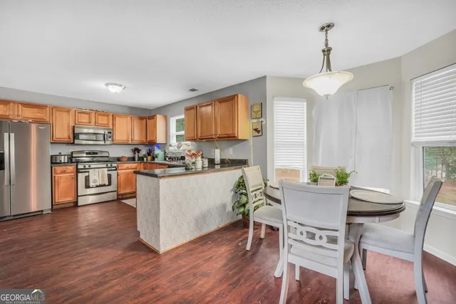 a kitchen with stainless steel appliances a dining table chairs stove refrigerator and microwave