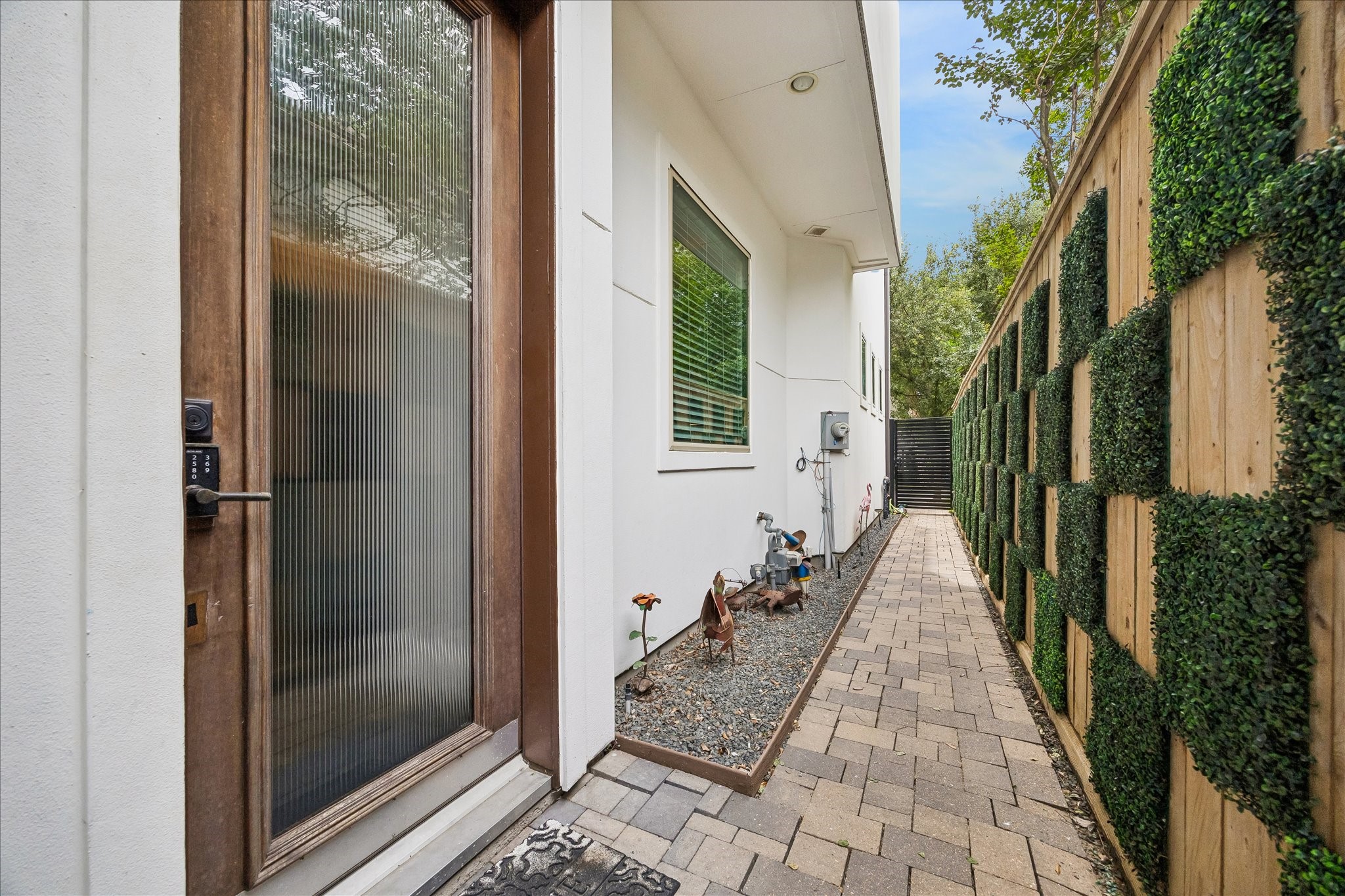 1208 Welch Street Houston, TX 77006 - Photo 12 of 35 The main entrance is on the side of the home, with wide pavered walkway to the front drive and tailored fence with checkerboard ivy detail.