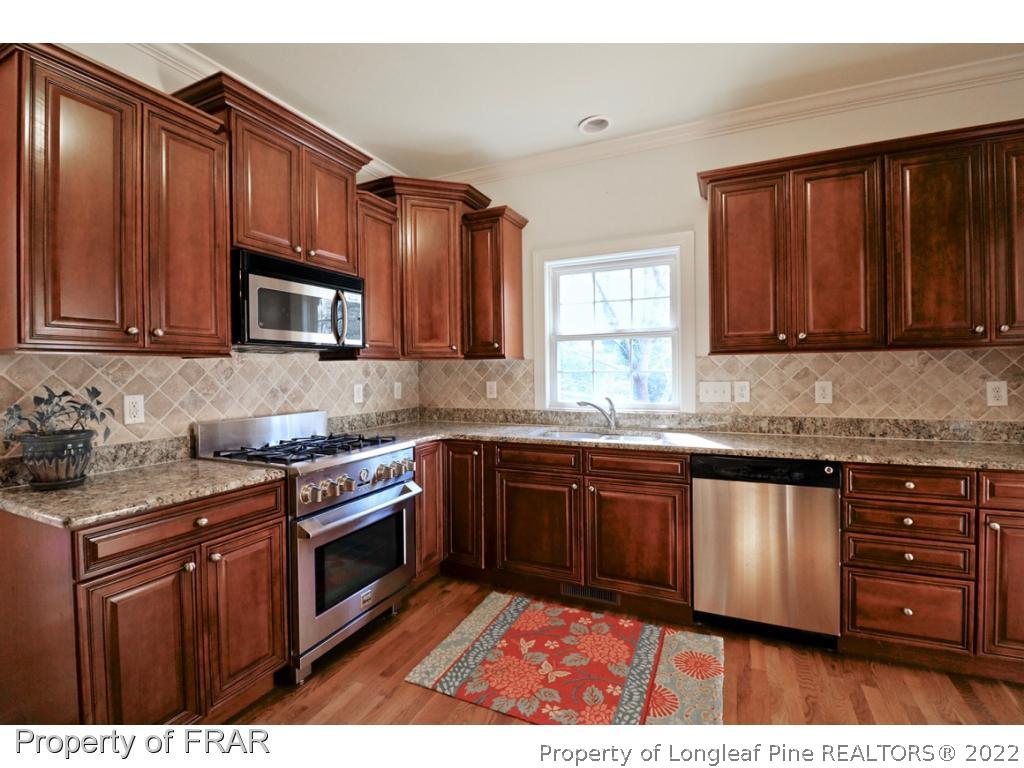 150 Lost Tree Road Pinehurst, NC 28374 - Photo 13 of 36 a kitchen with stainless steel appliances granite countertop wooden cabinets a stove a sink and dishwasher