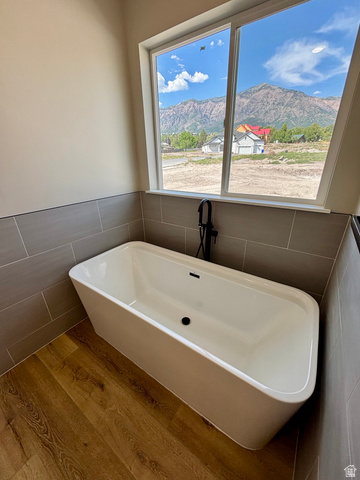 1184 West 3250 North Ogden, UT 84414 - Photo 34 of 69 Freestanding soaking tub with a matte black floor-mounted faucet, set against a tiled accent wall and lvp wood style flooring