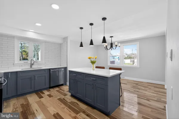 a kitchen with kitchen island granite countertop a sink cabinets and wooden floor