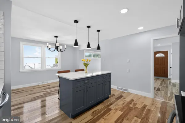 a kitchen with granite countertop a table chairs refrigerator and microwave