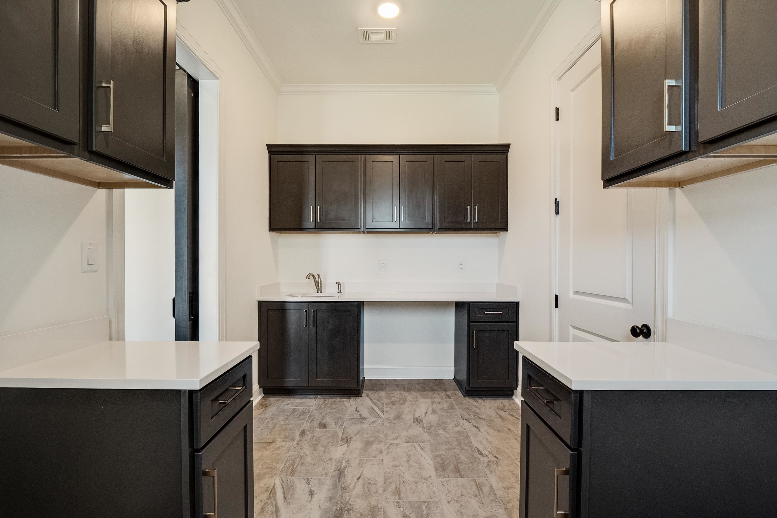 237 Beckham Drive Collierville, TN 38017 - Photo 26 of 40 Kitchen featuring a sink, visible vents, light countertops, ornamental molding, and dark brown cabinets