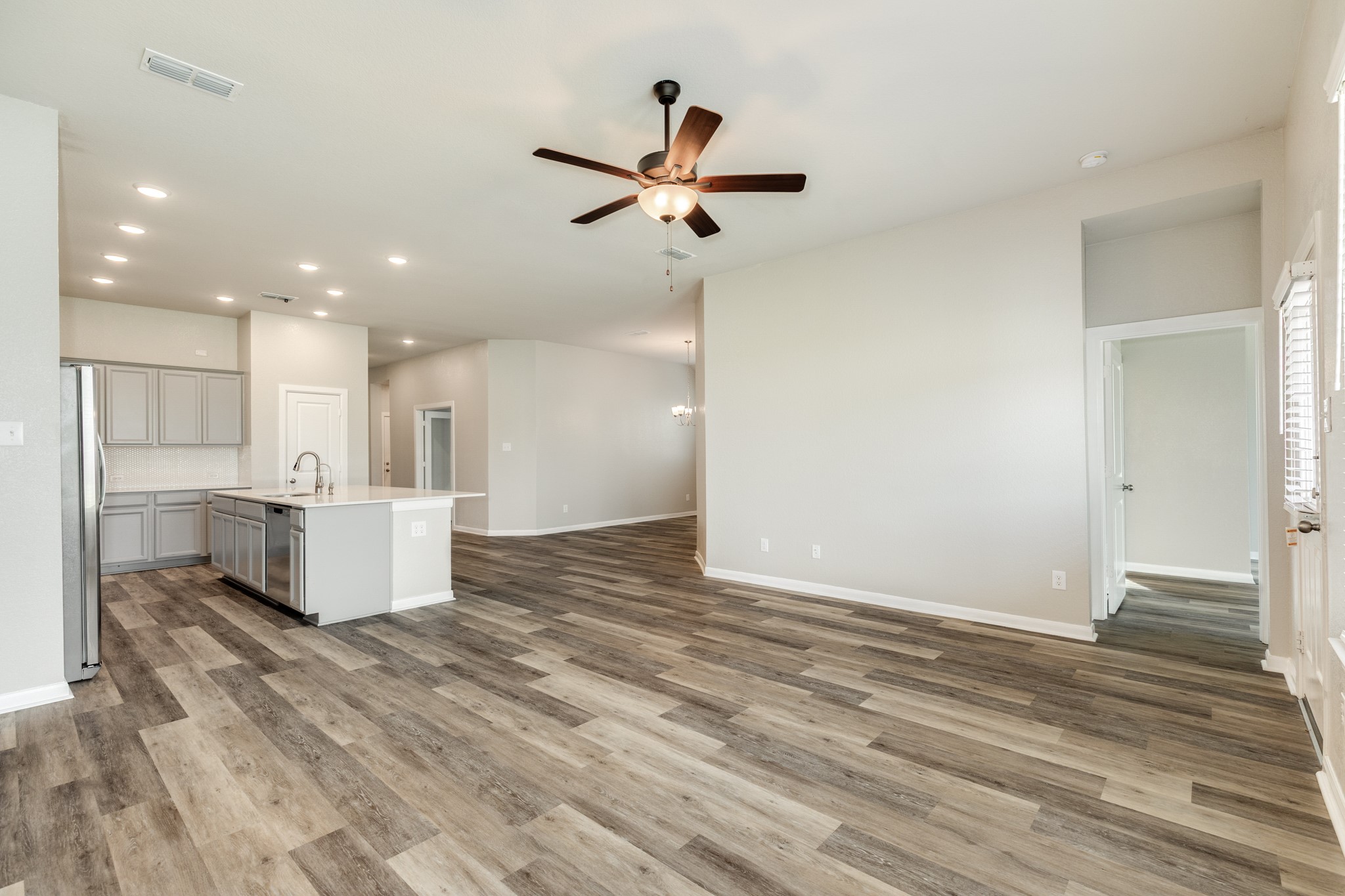 4946 Hitchings Court Rosharon, TX 77583 - Photo 15 of 49 This view highlights the open concept, showcasing the effortless transition from the dining area, through the kitchen, and into the family room. The door on the right provides access to the primary bedroom.