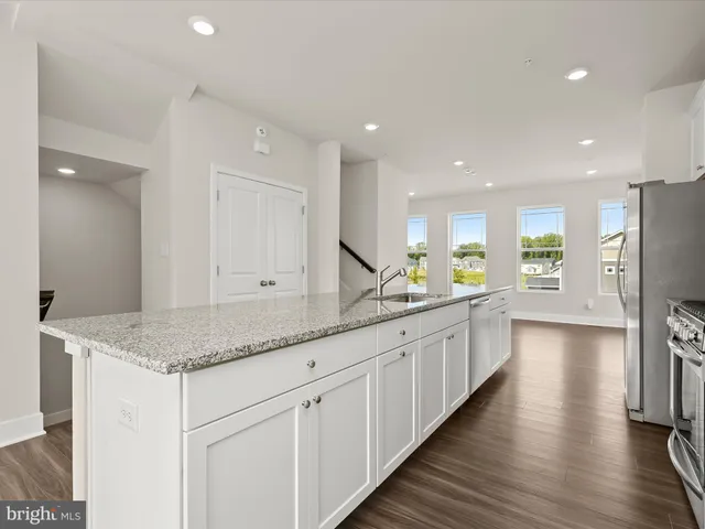 a large white kitchen with stainless steel appliances granite countertop a large counter top and a refrigerator