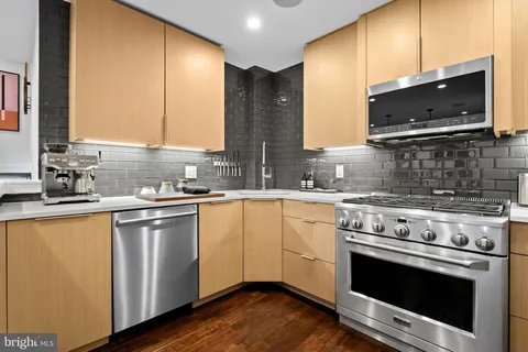 a kitchen with stainless steel appliances granite countertop a stove a refrigerator a kitchen island a dining table and chairs