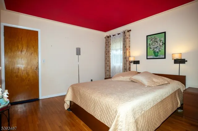 a bedroom with a bed and a bookshelf with wooden floor