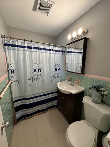 a bathroom with a sink a toilet a mirror and shower curtain