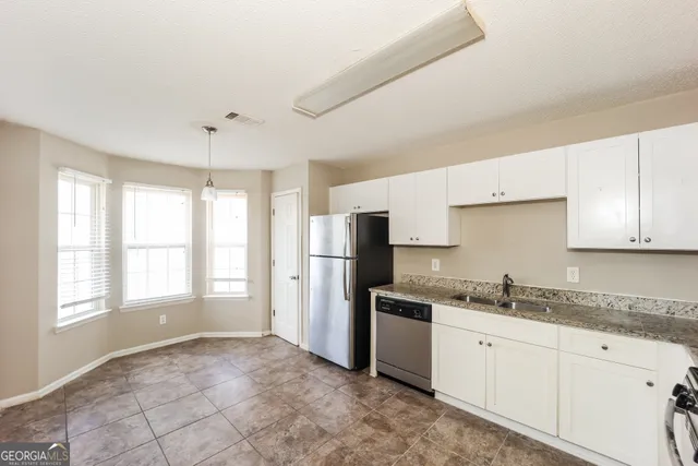 a kitchen with stainless steel appliances granite countertop a refrigerator a stove a sink a microwave oven with a dining table and chairs