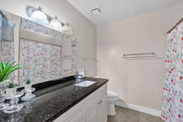 a bathroom with a granite countertop sink a toilet and a shower curtain