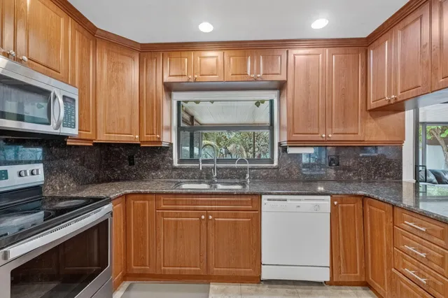 a kitchen with stainless steel appliances granite countertop a sink a stove a microwave cabinets and a refrigerator