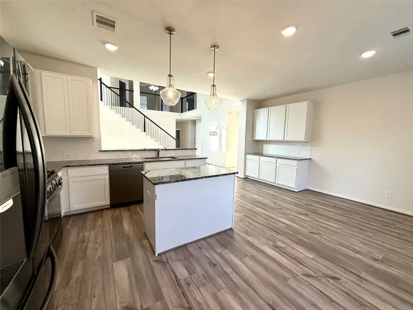 a kitchen with stainless steel appliances granite countertop a sink a stove and a wooden floors