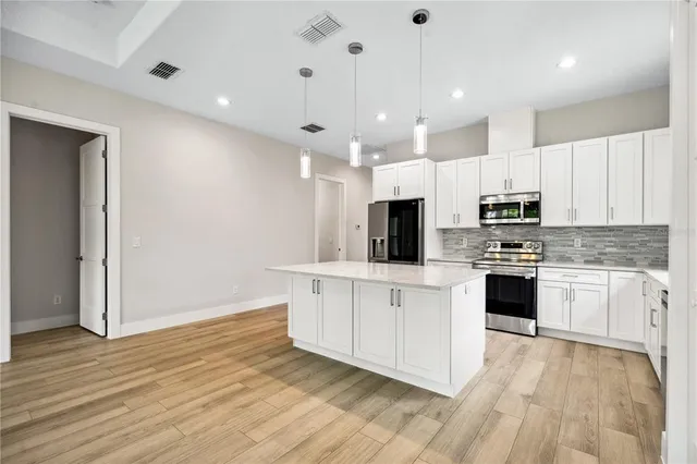 a large kitchen with cabinets wooden floor and stainless steel appliances