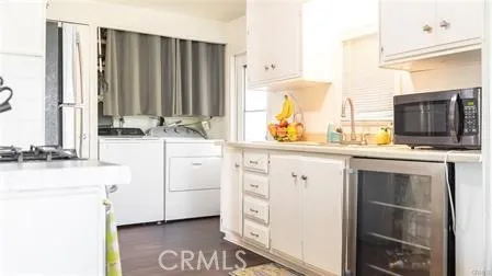 a kitchen with stainless steel appliances granite countertop a refrigerator a sink and white cabinets with wooden floor