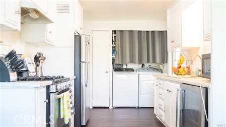 1134 Villa Calimesa Lane, Unit 42 Calimesa, CA 92320 - Photo 25 of 36 a kitchen with stainless steel appliances granite countertop a refrigerator a sink and white cabinets with wooden floor