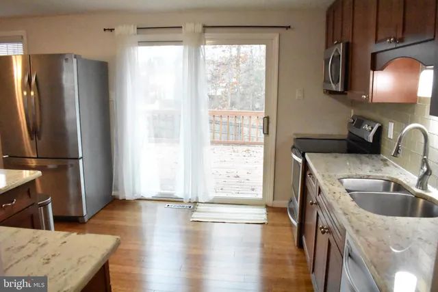 a kitchen with stainless steel appliances granite countertop a sink a refrigerator a stove and a refrigerator with wooden floor