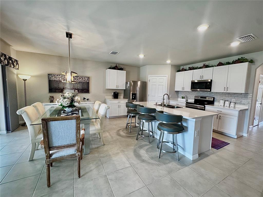 4077 Manatee Lane Punta Gorda, FL 33980 - Photo 11 of 35 a kitchen with stainless steel appliances kitchen island granite countertop a sink a stove a dining table and chairs
